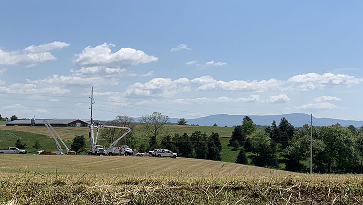 Utility trucks working on power lines in a field