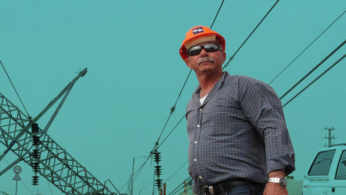 Wide shot of a utility worker gazing beyond the camera in front of collapsed pylons.