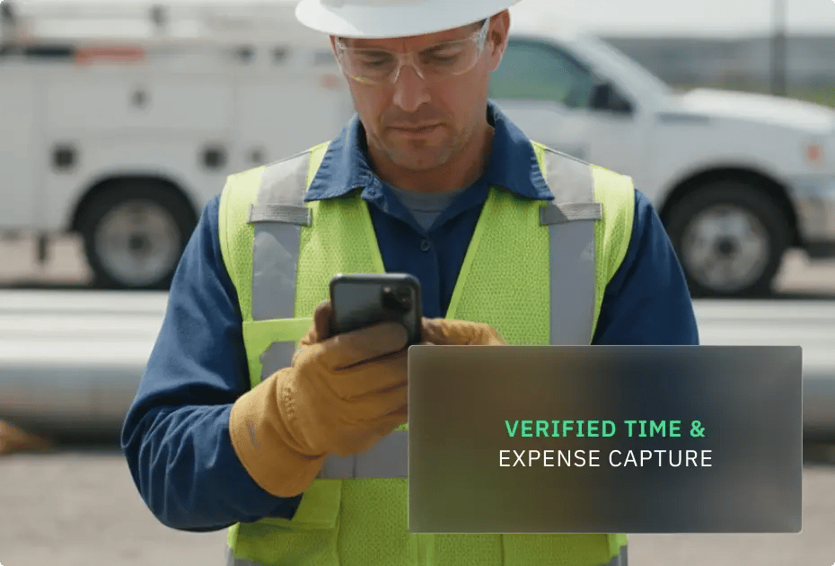 Worker in safety gear using smartphone at construction site.