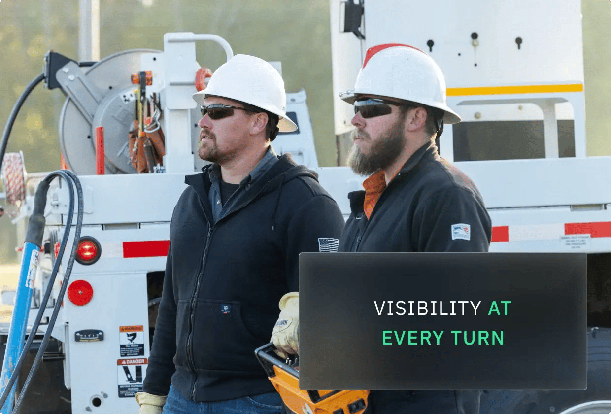 Two workers with hard hats stand before utility vehicles, emphasizing safety and visibility.