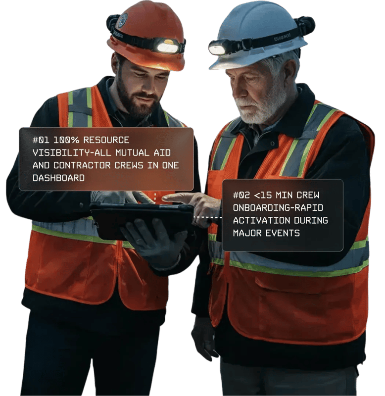 Two utility crew workers wearing safety gear review information together on a tablet during field operations.