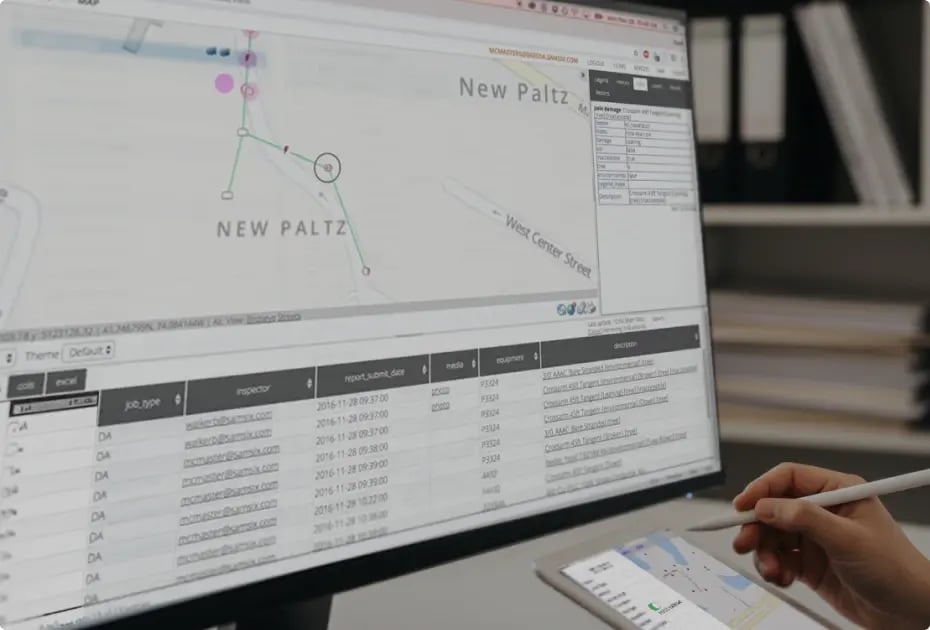 Person analyzing geographic data on computer with tablet.