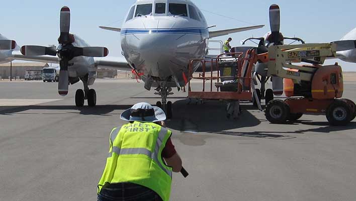 A utility worker in front of a small private plane