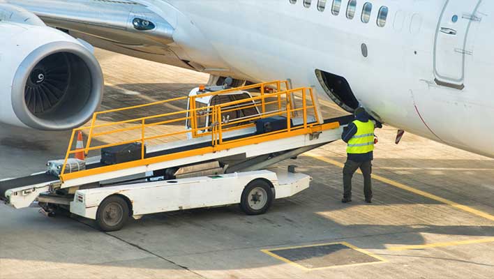 An airline utility worker attaching a luggage conveyer belt to a plane
