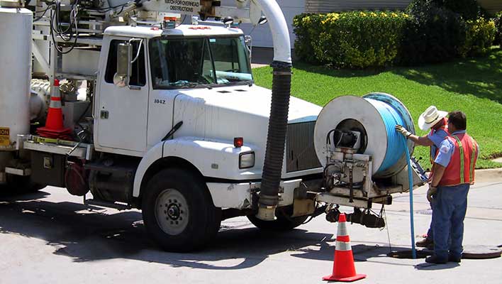 Utility crews lowering cables into a sewer