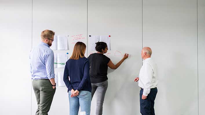 Team members diagraming a process on paper taped on the wall