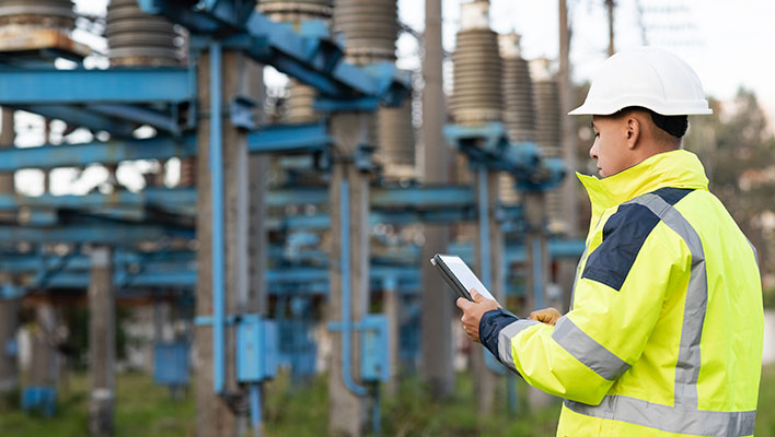 A utility worker using ARCOS utility software on a tablet to check power levels at a plant