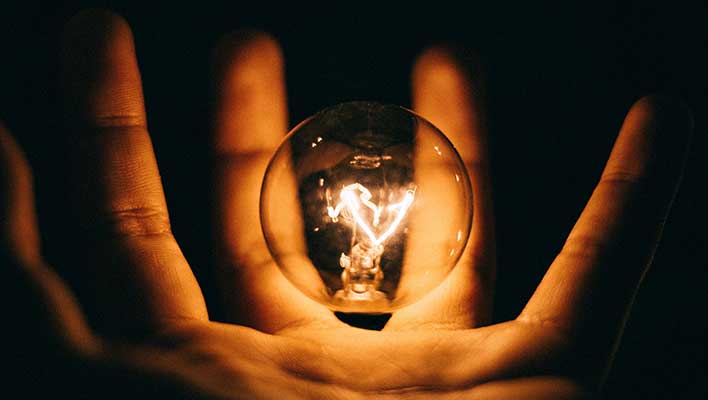 Hand holding an illuminated lightbulb