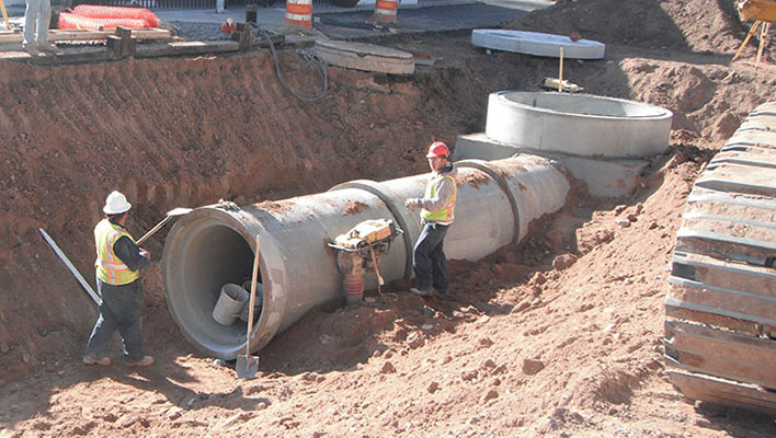 Utility workers installing a large drainage pipe