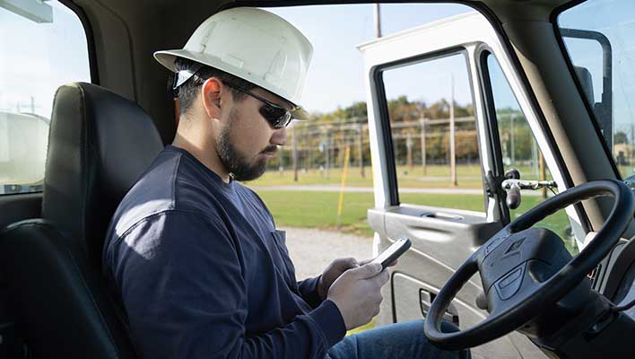 A gas utility worker using ARCOS's Automated Callouts App while sitting in his car