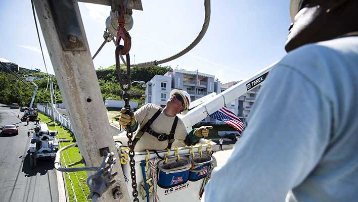 Two line works in a bucket truck inspecting a power transmission line