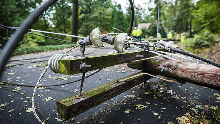 A downed power line with utility workers in the background