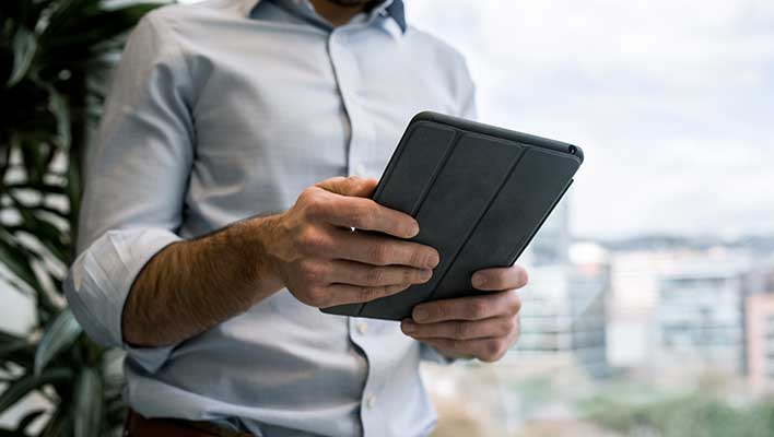 businessman with sleeves rolled up, looking at a tablet