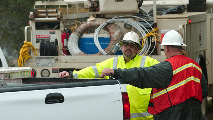 Two utility workers talking by a white truck