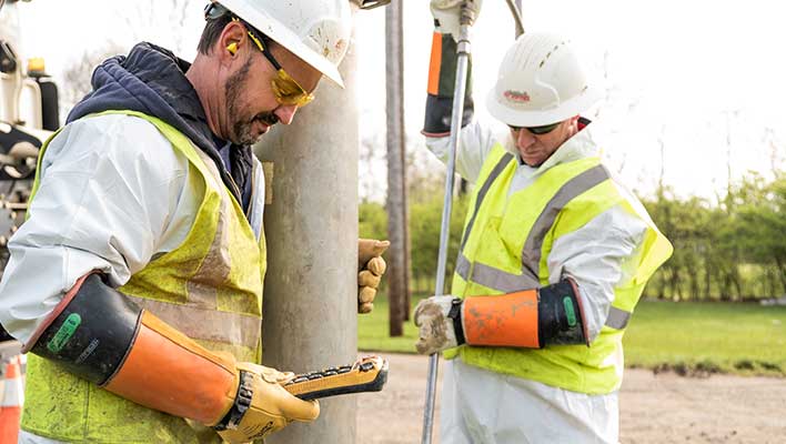 Two utility workers inspecting their work using digital meters