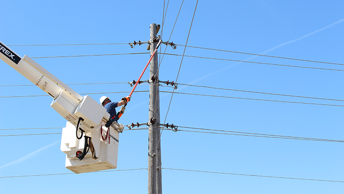 Lineman in a bucket truck's bucket working on a power line