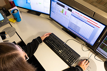 A dispatch coordinator scrolls crew rosters, while scanning outage management system.
