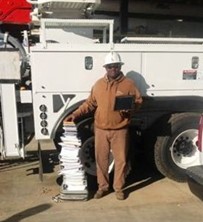 A utility worker standing next to binders of paperwork almost as tall as him