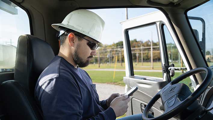 A electric utility worker using ARCOS's Automated Callouts App while sitting in his car