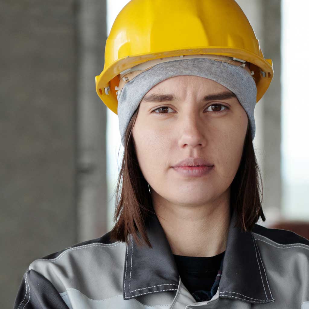 Portrait view of a young woman in a hardhat looking at the viewer