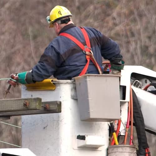 A utility crewman standing in cherry picker getting ready to work on a power line