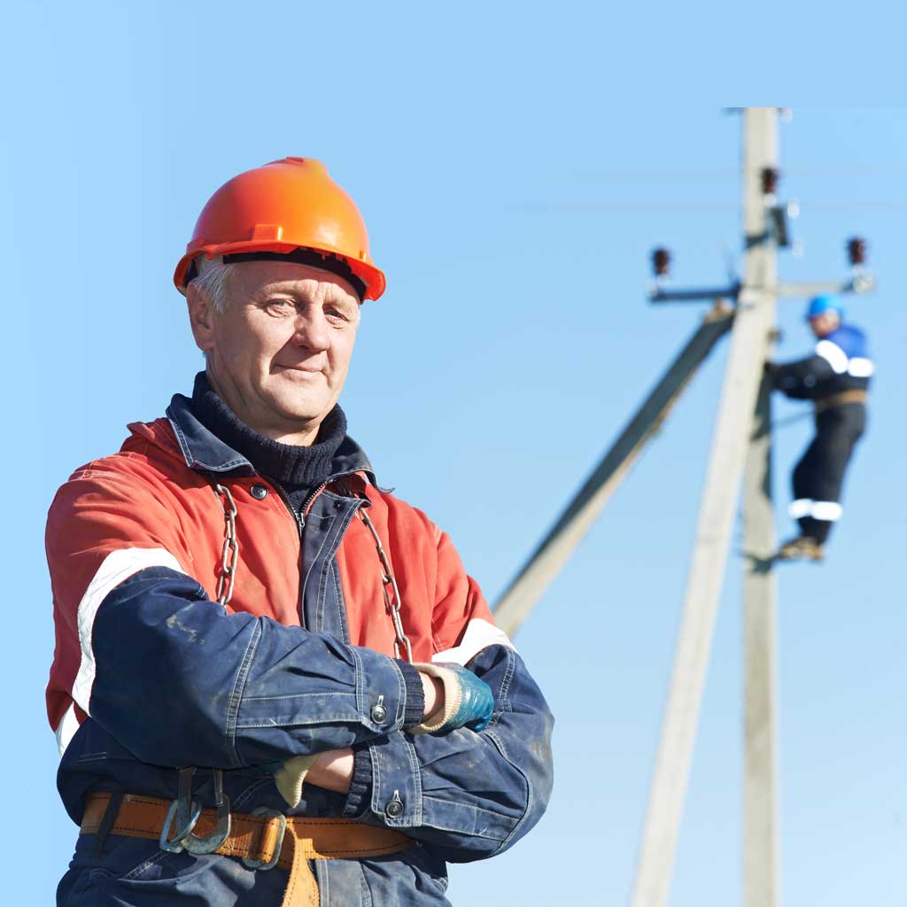 Older man with crossed arms, wearing a hard hat, looking at the viewer
