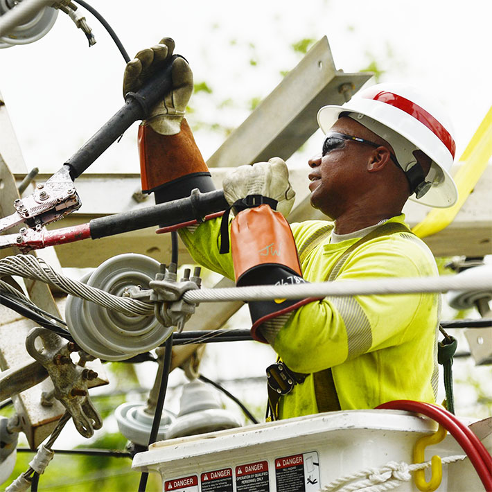 A utility worker tightening a power line in a cherry picker
