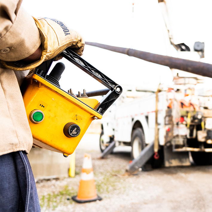 A close up of a utility worker holding a remote electrical switch