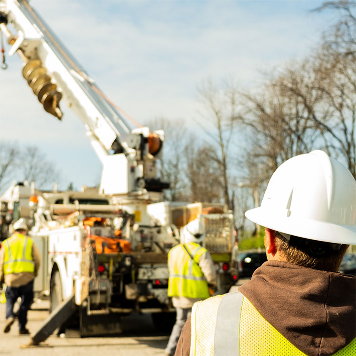 Over-the-shoulder view of utility workers setting up a cherry picker from the ground