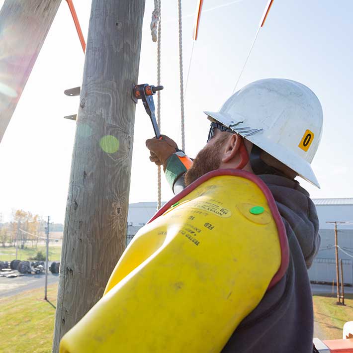 A utility worker screwing a bolt into a power line