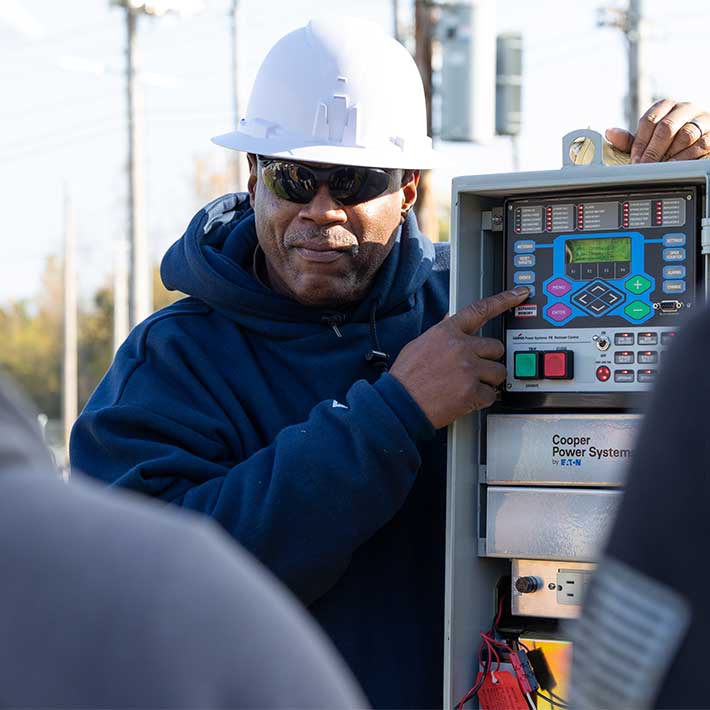 A utility worker pointing towards a power console
