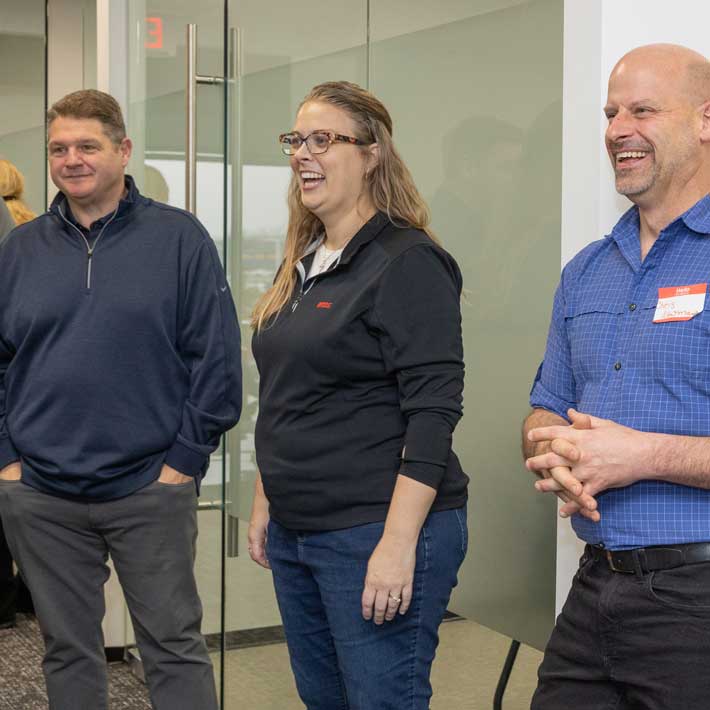 Three Arcos team members smiling in a meeting room