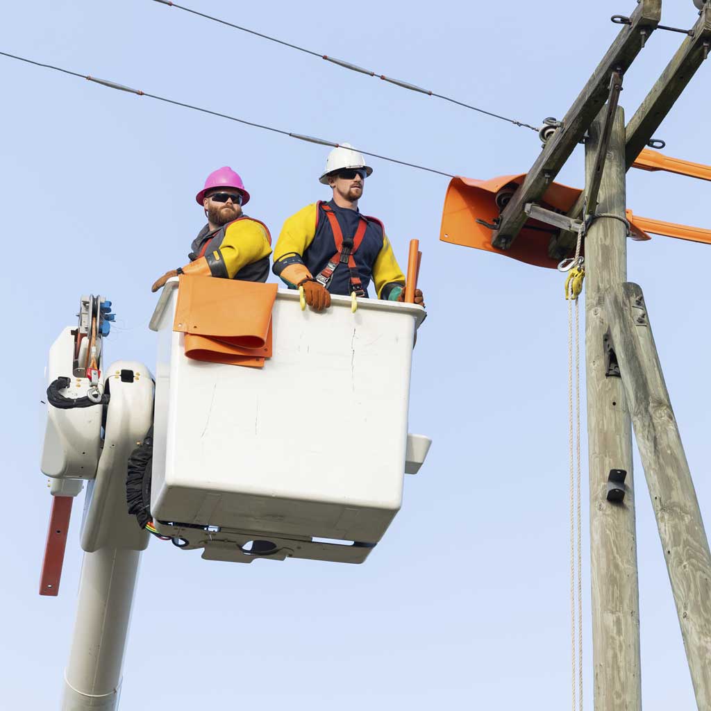 Two utility workers in a cherry picker setting insulated rubber on a power line