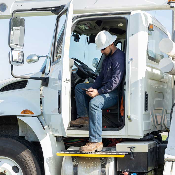 A utility worker checking his ARCOS Callout app in a large white truck