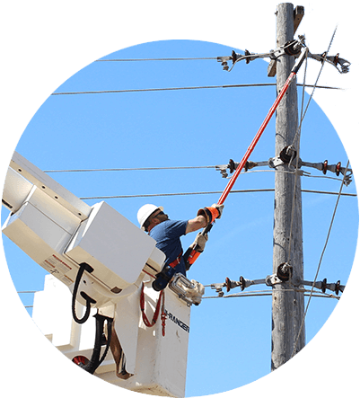 A utility worker reaching up with a pole to adjust a power line
