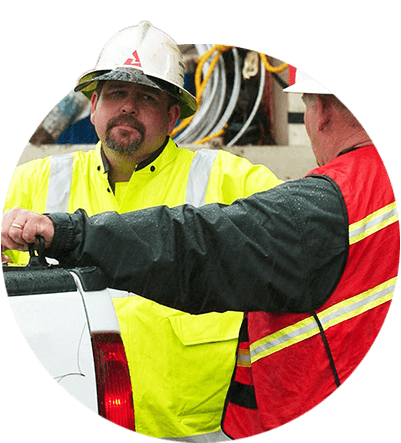 Two utility workers talking by a white truck