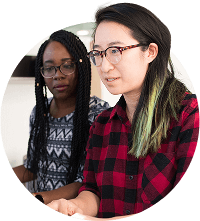 Two women reviewing utility performance data from ARCOS on a computer