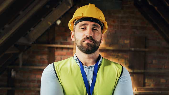 Young man wearing a high-visibility vest and a hard hat, looking at the viewer
