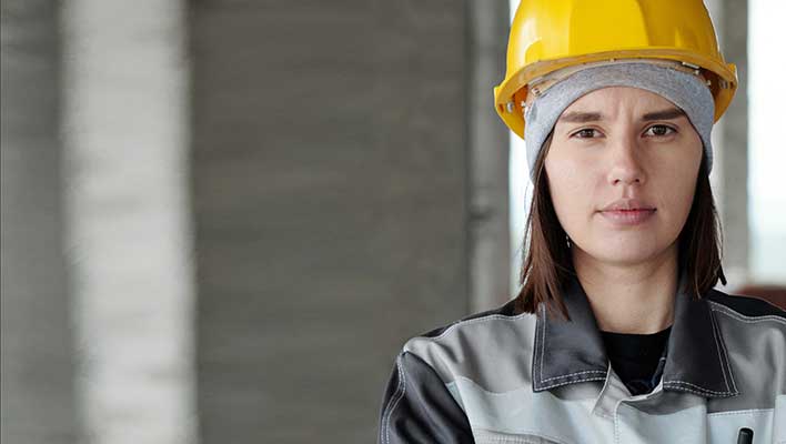 Portrait view of a young woman in a hardhat looking at the viewer