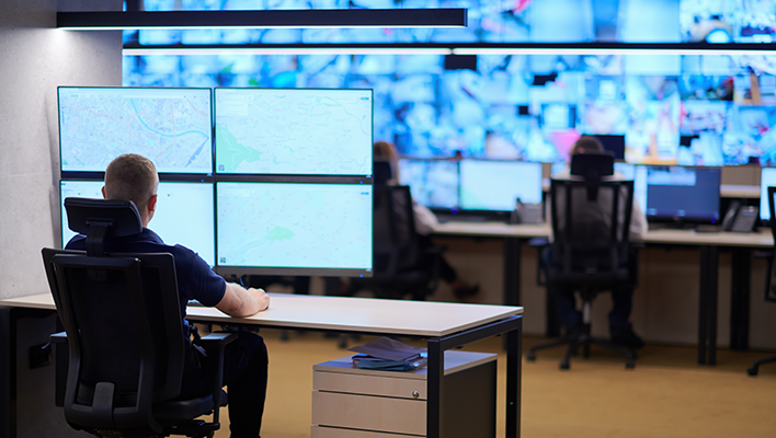 Business person working on several monitors within a control room