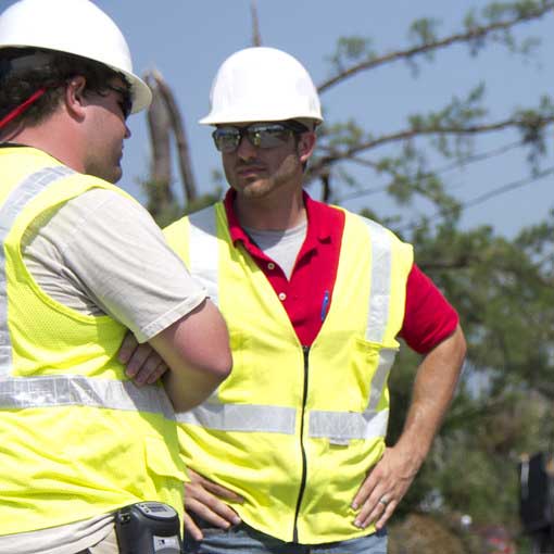 Two workers in hard hats talking with each other