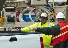 Two utility workers talking by a white truck